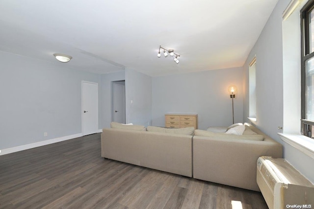 living room featuring a wall unit AC, baseboards, and wood finished floors