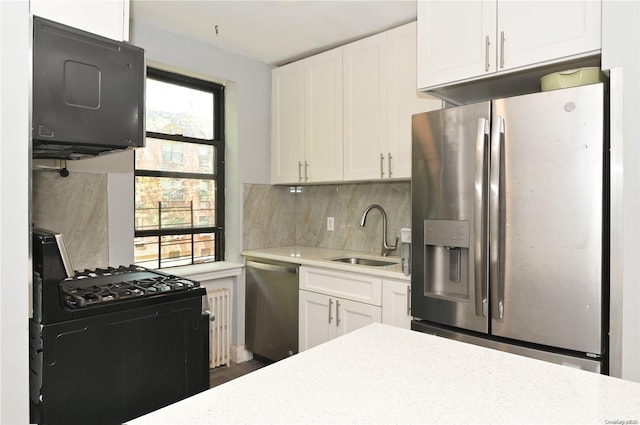 kitchen featuring tasteful backsplash, appliances with stainless steel finishes, light countertops, white cabinetry, and a sink