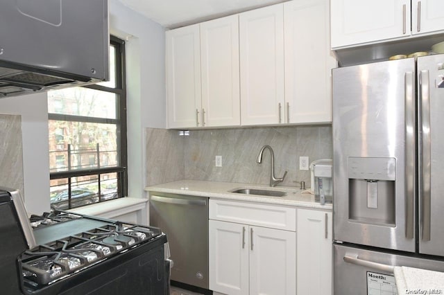 kitchen featuring white cabinets, backsplash, stainless steel appliances, and a sink