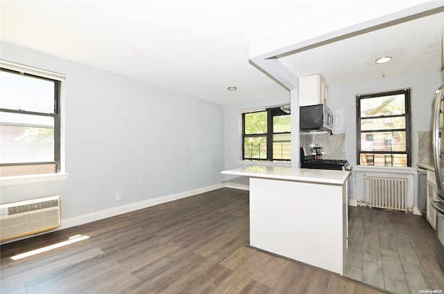 kitchen featuring light countertops, radiator heating unit, appliances with stainless steel finishes, white cabinetry, and a peninsula