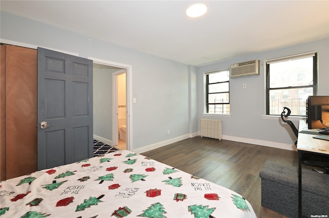 bedroom with radiator, a wall unit AC, baseboards, and dark wood finished floors