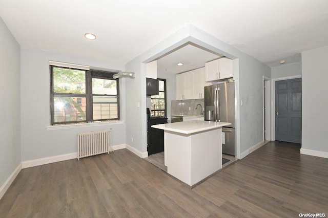 kitchen featuring white cabinets, dark hardwood / wood-style floors, decorative backsplash, appliances with stainless steel finishes, and radiator heating unit