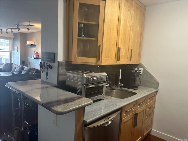 kitchen featuring kitchen peninsula, backsplash, stainless steel dishwasher, sink, and stone countertops