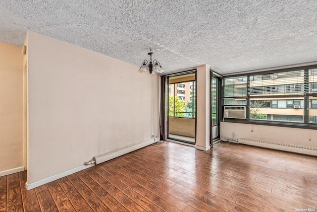 spare room with a textured ceiling, hardwood / wood-style flooring, baseboard heating, and a notable chandelier