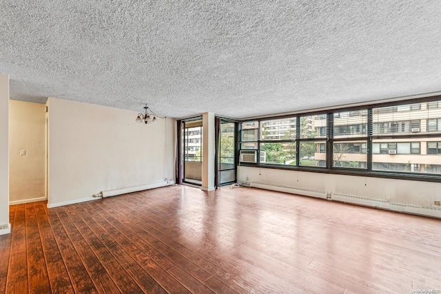 empty room featuring a chandelier, wood-type flooring, a textured ceiling, and baseboard heating