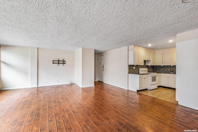 unfurnished living room featuring sink, a textured ceiling, and light hardwood / wood-style flooring