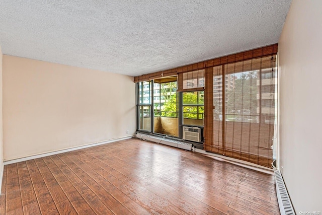 unfurnished room featuring hardwood / wood-style floors, a textured ceiling, and a baseboard heating unit