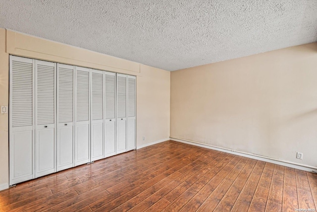 unfurnished bedroom featuring a textured ceiling and dark wood-type flooring