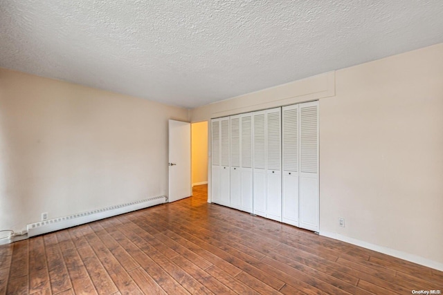 unfurnished bedroom with baseboard heating, a closet, dark hardwood / wood-style flooring, and a textured ceiling