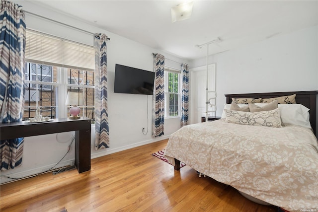 bedroom with hardwood / wood-style floors and track lighting