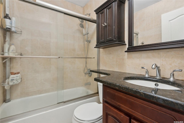 full bathroom featuring vanity, shower / bath combination with glass door, backsplash, toilet, and tile walls