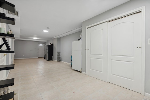 basement featuring stainless steel fridge, white fridge, and light tile patterned floors