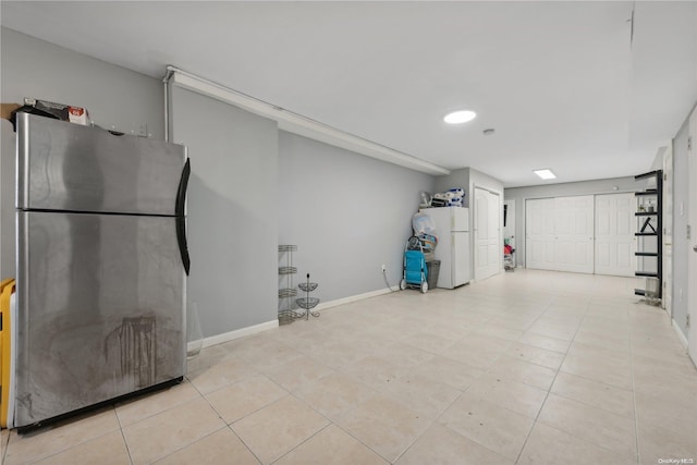 basement featuring white refrigerator, light tile patterned floors, and stainless steel refrigerator