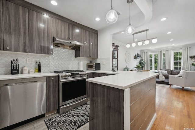 kitchen featuring stainless steel appliances, light hardwood / wood-style flooring, decorative light fixtures, decorative backsplash, and dark brown cabinets