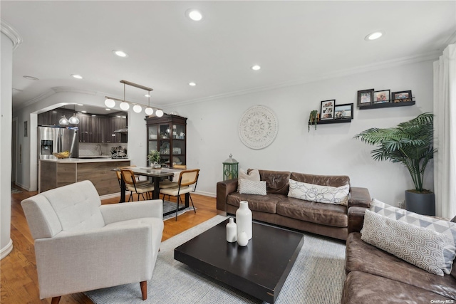 living room with light hardwood / wood-style floors, ornamental molding, sink, and vaulted ceiling