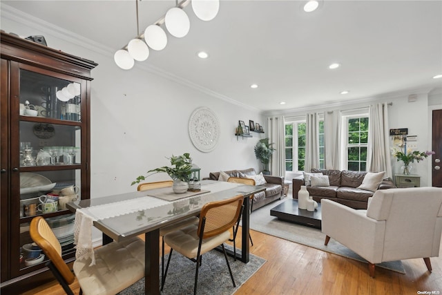 dining area with light hardwood / wood-style floors and ornamental molding