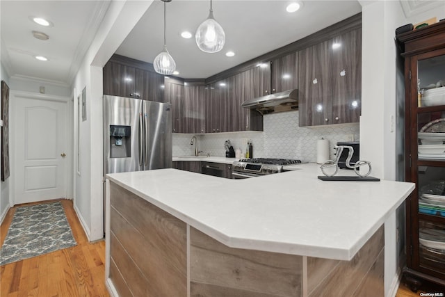 kitchen with kitchen peninsula, appliances with stainless steel finishes, light wood-type flooring, sink, and decorative light fixtures