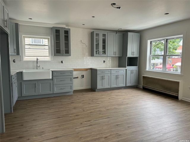 kitchen featuring sink, gray cabinets, light wood-type flooring, tasteful backsplash, and a baseboard radiator