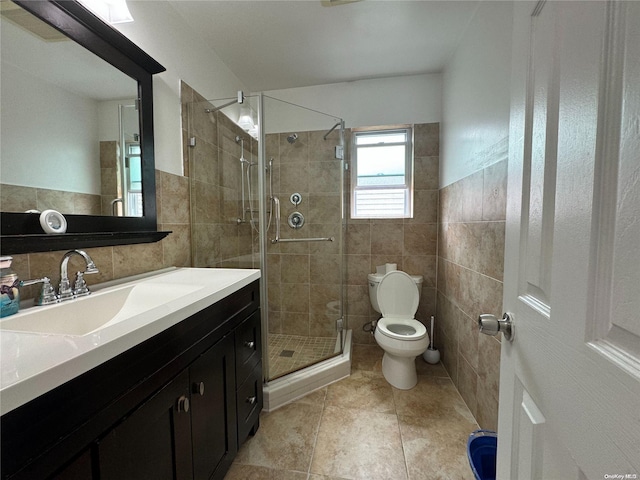 bathroom featuring vanity, a shower with door, toilet, and tile walls