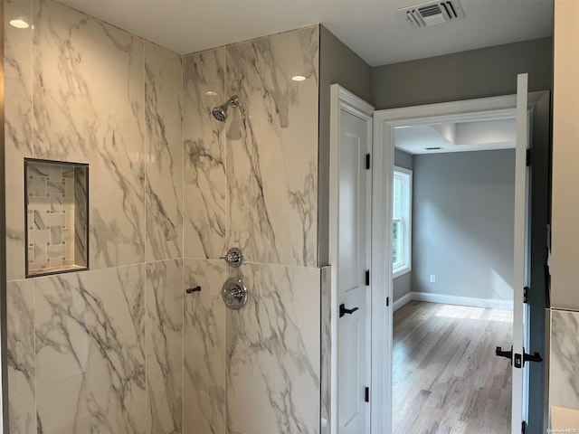 bathroom with wood-type flooring and tiled shower