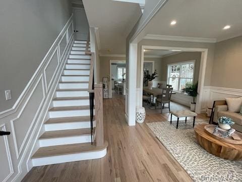 stairs featuring wood-type flooring and crown molding