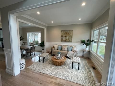 living room with light wood-type flooring and ornamental molding