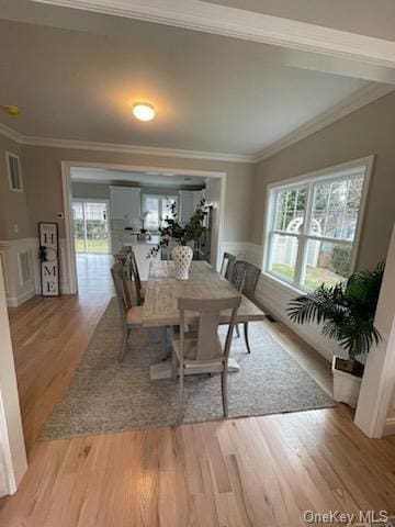 dining space with light wood-type flooring, a wealth of natural light, and ornamental molding