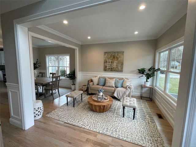 living room featuring light wood finished floors, recessed lighting, ornamental molding, and wainscoting