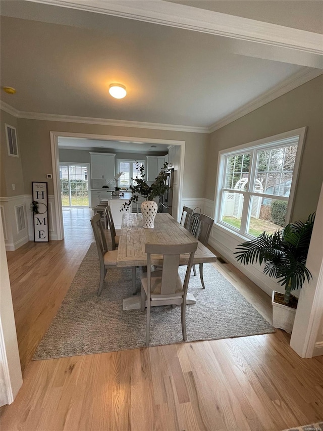 dining area with ornamental molding, visible vents, plenty of natural light, and light wood finished floors