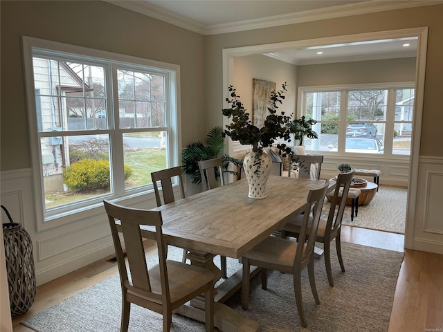 dining space featuring a decorative wall, a wainscoted wall, recessed lighting, light wood-style floors, and ornamental molding