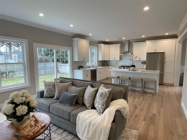 living area with light wood finished floors, baseboards, ornamental molding, and recessed lighting