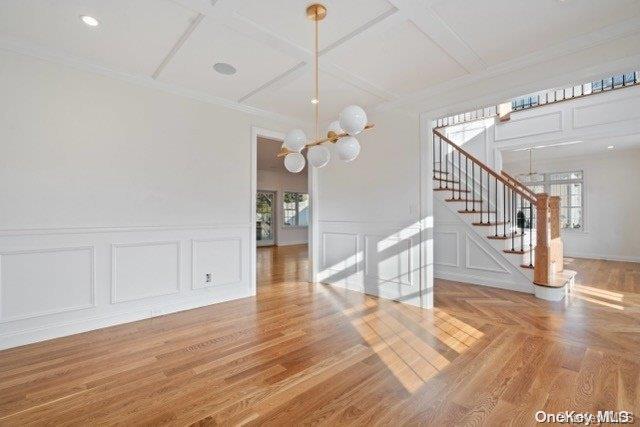 unfurnished dining area with wood-type flooring, coffered ceiling, and an inviting chandelier