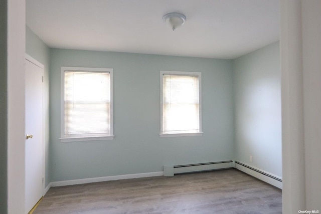 empty room with a baseboard heating unit, light hardwood / wood-style floors, and a healthy amount of sunlight