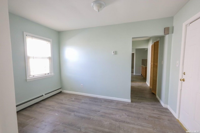 empty room with light hardwood / wood-style floors and a baseboard heating unit