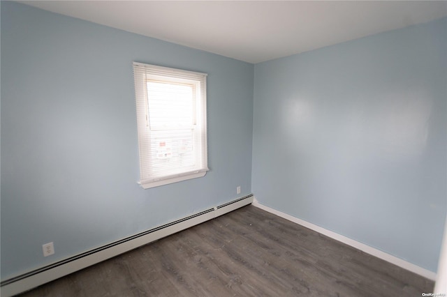 empty room featuring dark hardwood / wood-style flooring and a baseboard heating unit