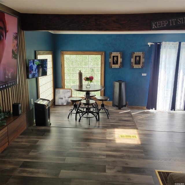 dining room with beam ceiling and dark wood-type flooring