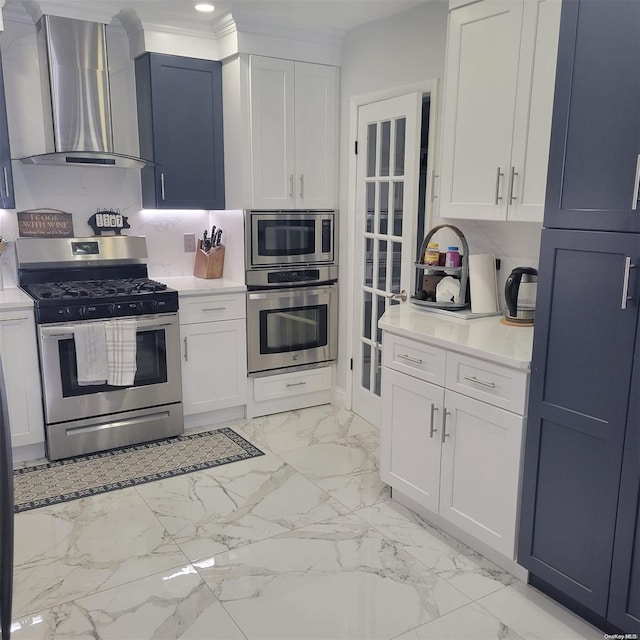 kitchen with wall chimney exhaust hood, decorative backsplash, white cabinetry, and stainless steel appliances