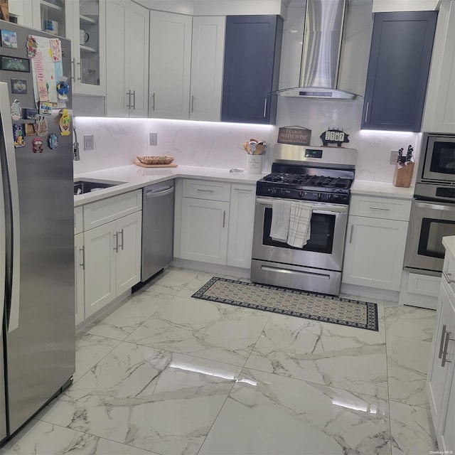 kitchen with appliances with stainless steel finishes, backsplash, white cabinetry, and wall chimney range hood