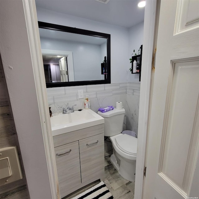 bathroom with vanity, tile walls, and toilet