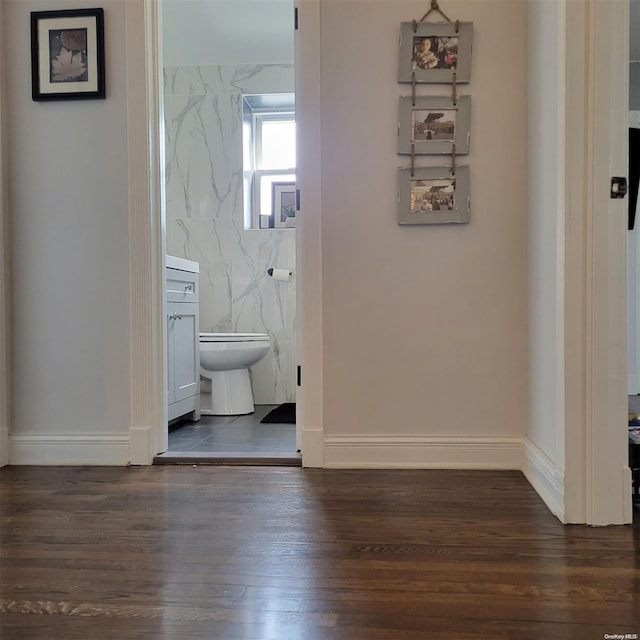 hall with tile walls and dark wood-type flooring