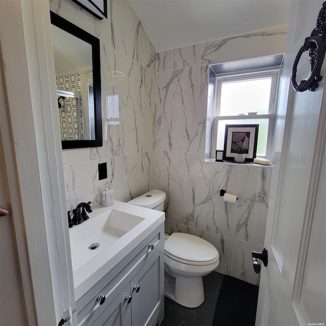 bathroom featuring vanity, tile walls, and toilet