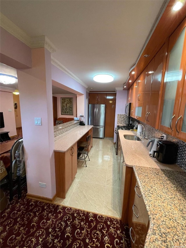 kitchen with light stone countertops, sink, appliances with stainless steel finishes, and ornamental molding