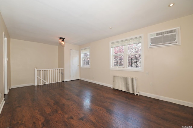 empty room with radiator heating unit, dark hardwood / wood-style flooring, and an AC wall unit