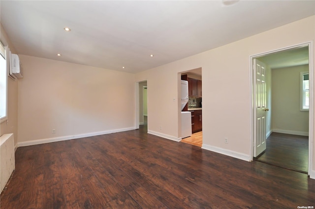 unfurnished living room featuring radiator heating unit, dark hardwood / wood-style flooring, and a wall mounted air conditioner