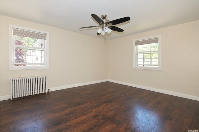 empty room featuring dark hardwood / wood-style flooring, radiator heating unit, and ceiling fan