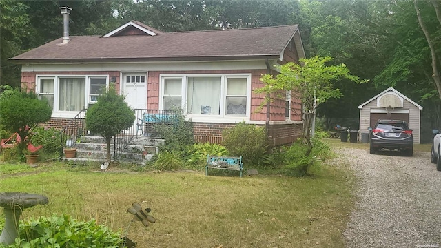 view of front of home featuring a garage, a front lawn, and an outdoor structure