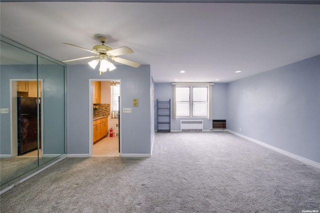 unfurnished living room featuring ceiling fan, radiator heating unit, and light carpet