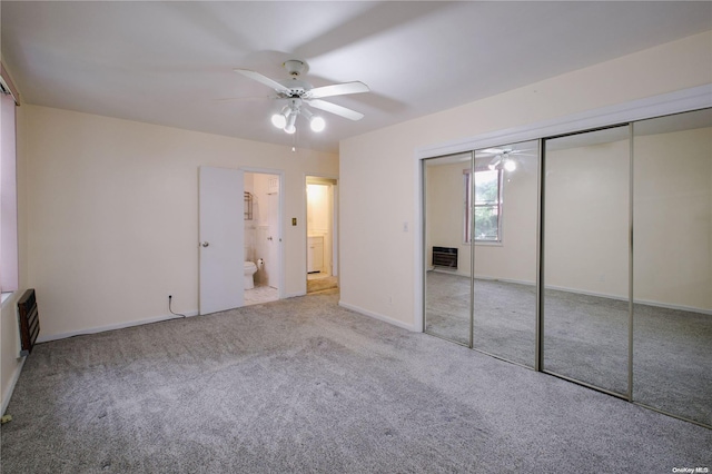 unfurnished bedroom featuring heating unit, ceiling fan, ensuite bath, and light carpet