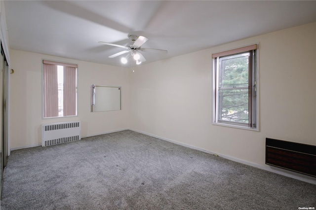 carpeted spare room with radiator and ceiling fan