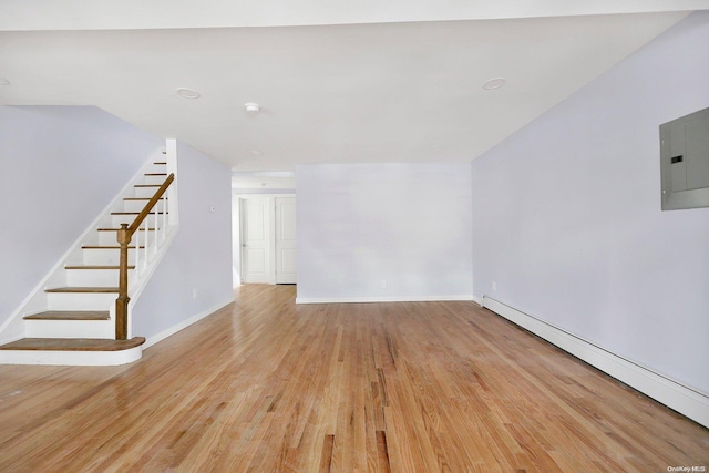 unfurnished living room with light wood-type flooring, a baseboard radiator, and electric panel